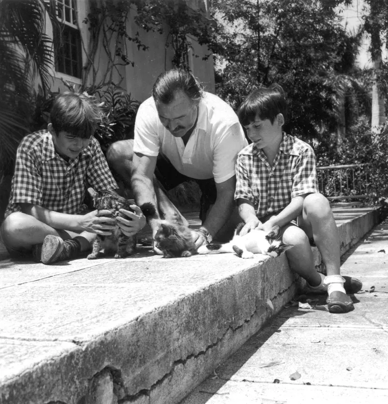 Эрнест Хемингуэй с сыновьями Патриком "Маусом" (слева) и Грегори "Джиджи" (справа) и их кошками Гуд Уиллом, Принцессой и Бойсом в их доме, Финка Вигия, Сан-Франциско де Паула, Куба.